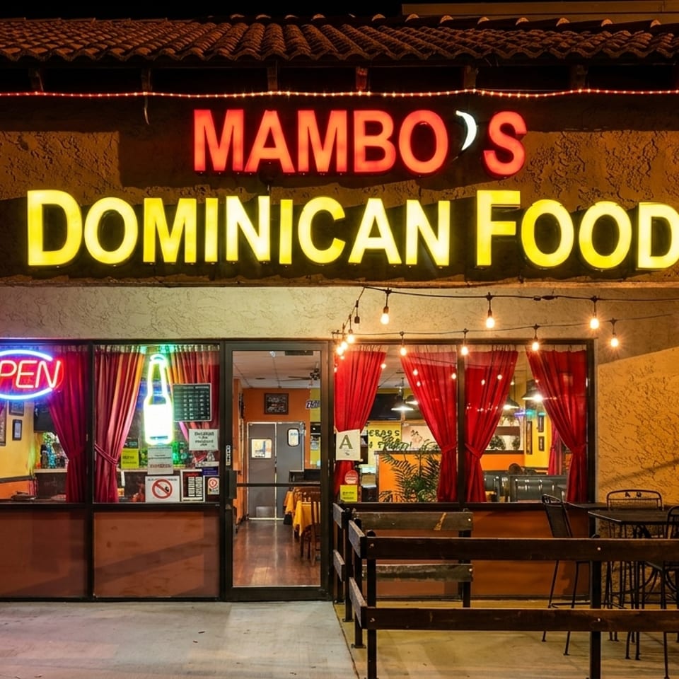 Mambo's Dominican Food restaurant exterior at night with glowing signs and outdoor seating.